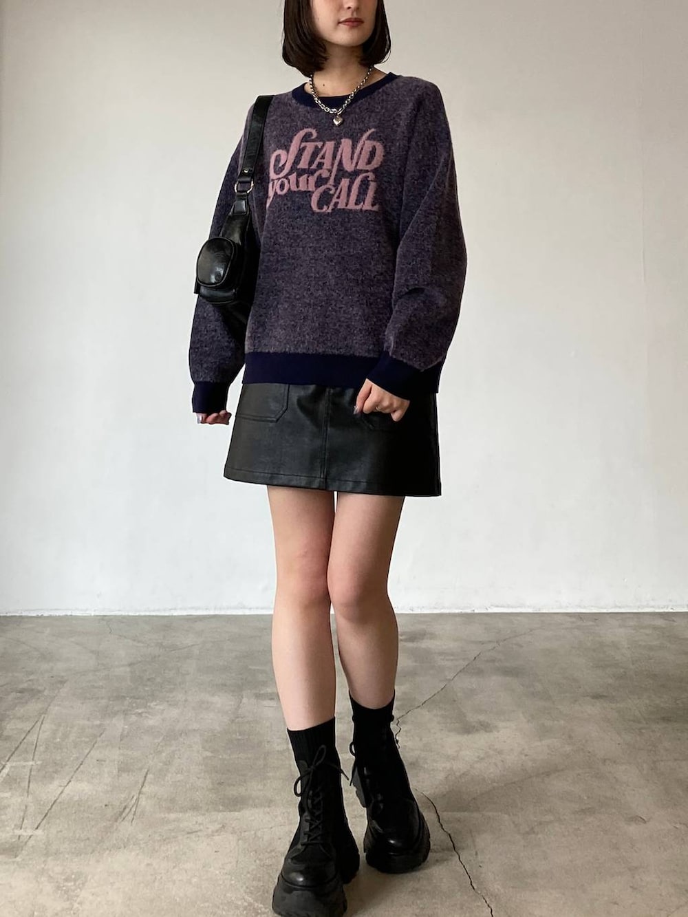 ブラック系のブーツ、ブラック系のスカート、ブラック系のショルダーバッグを着用したレディースの冬コーディネートの2枚目の写真