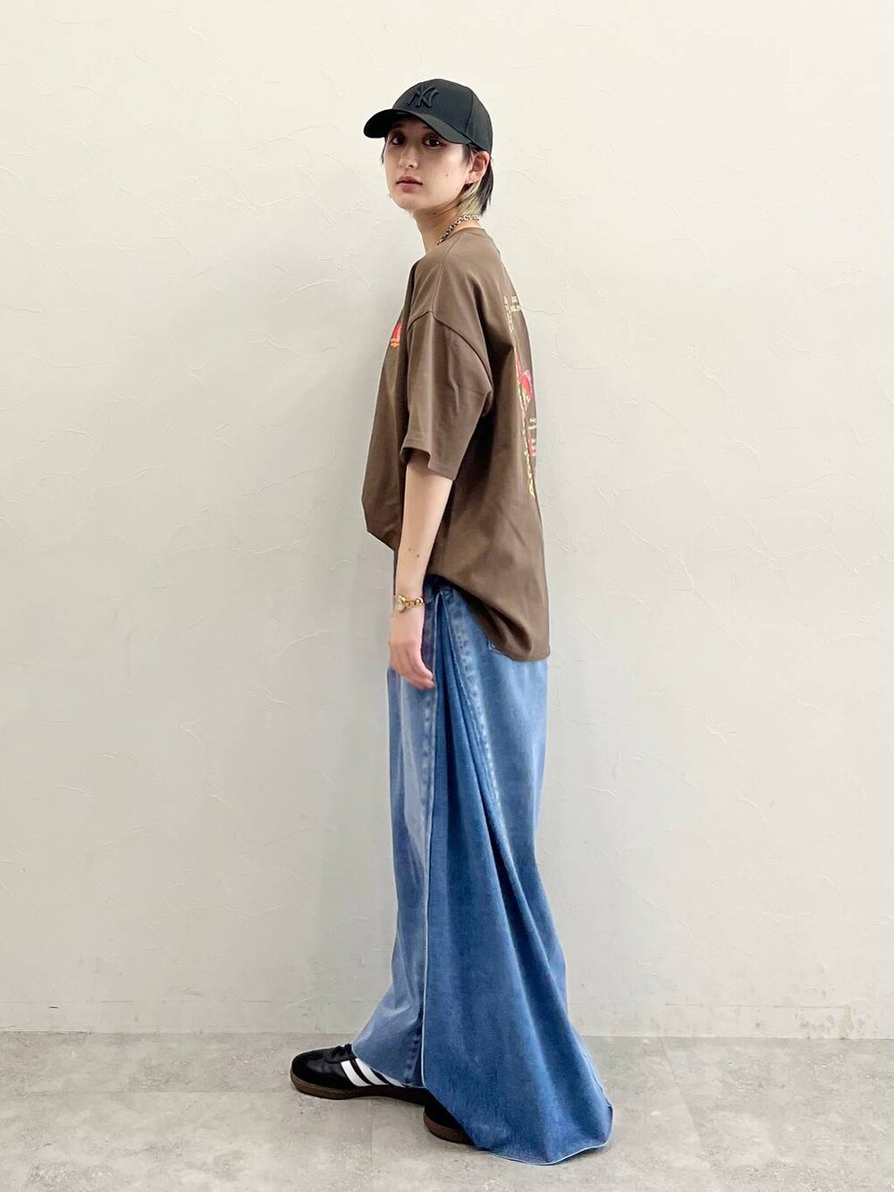 ブルー系のデニムパンツ、ブラック系のスニーカー、ブラウン系のTシャツ/カットソーを着用したレディースの春コーディネートの5枚目の写真