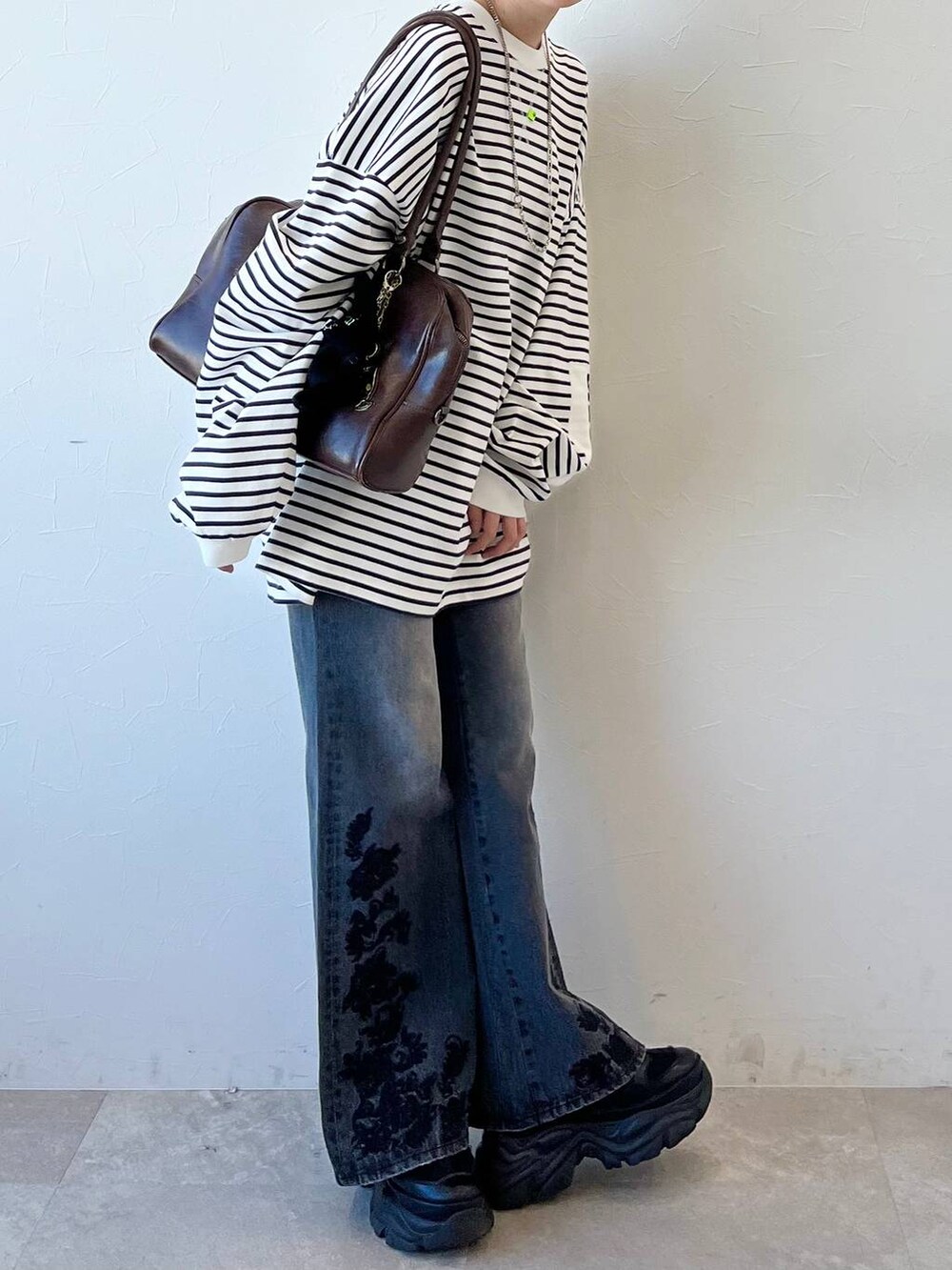 ブラック系のスニーカー、ブラウン系のボストンバッグ、ブラック系のデニムパンツを着用したレディースの春コーディネートの4枚目の写真