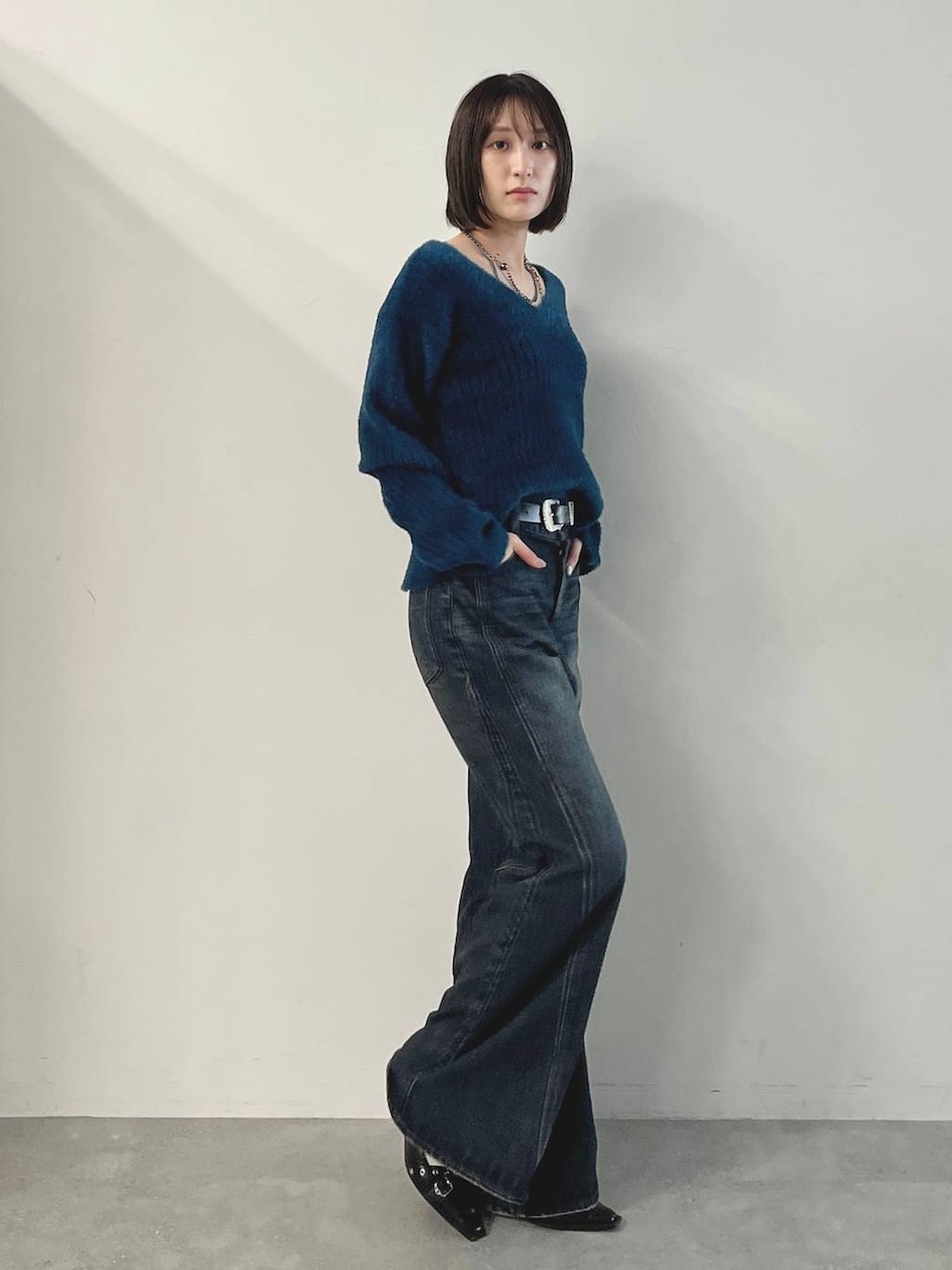 ブルー系のデニムパンツ、ブラック系のパンプス、グリーン系のニット/セーターを着用したレディースの秋コーディネートの5枚目の写真