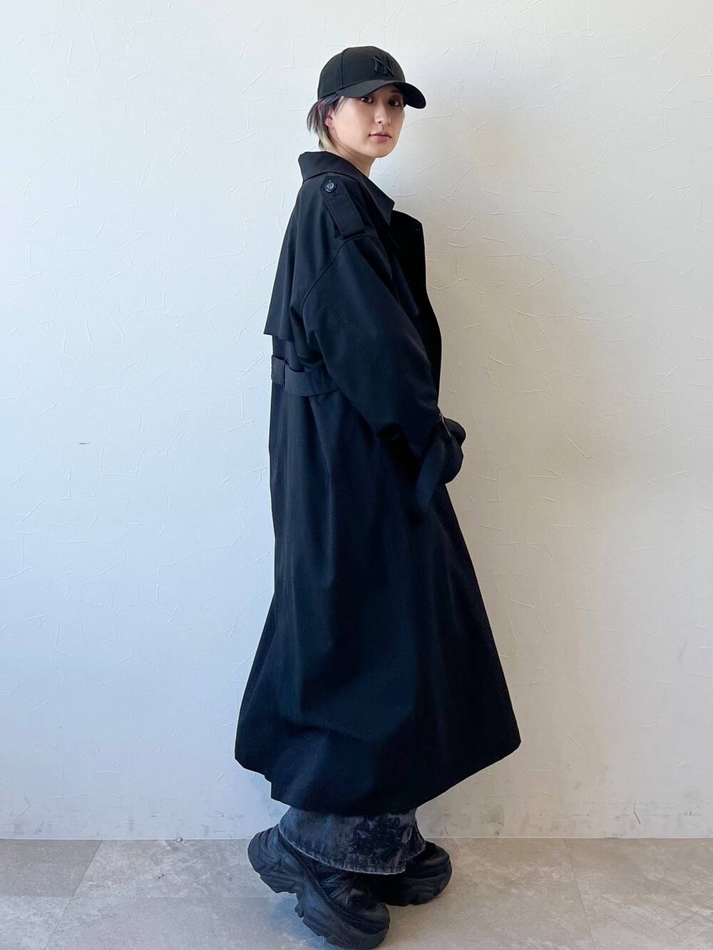 ブラック系のスニーカー、ブラック系のトレンチコート、ブラック系のデニムパンツを着用したレディースの春コーディネートの4枚目の写真