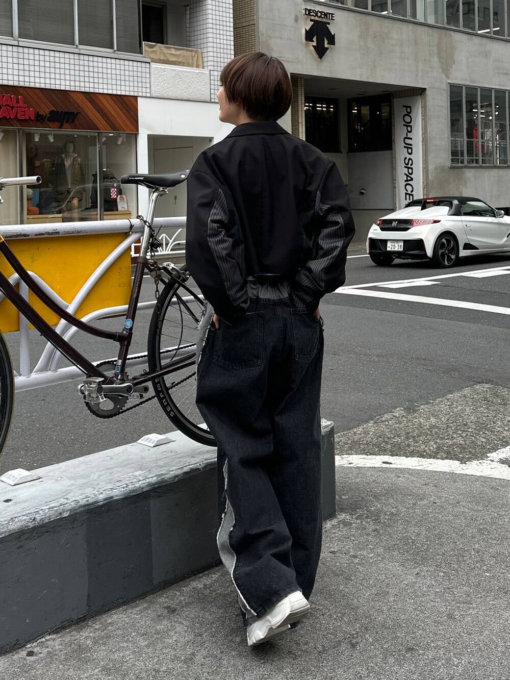 ブラック系のテーラードジャケット、ブラック系のデニムパンツ、ブルー系のスウェットを着用したレディースの春コーディネートの5枚目の写真