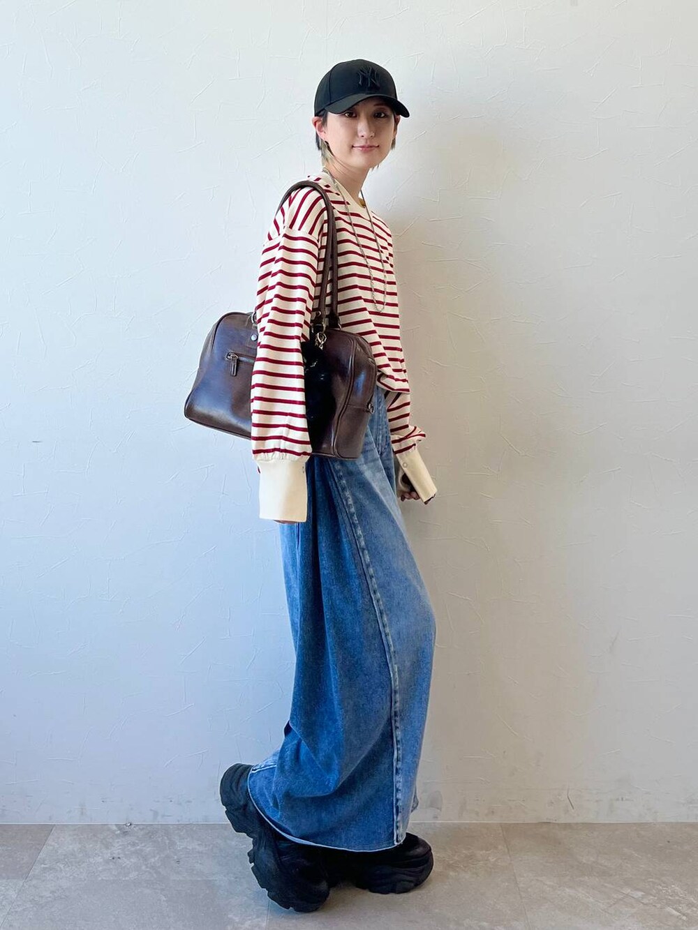 ブラック系のスニーカー、ブラウン系のボストンバッグ、ブルー系のデニムパンツを着用したレディースの春コーディネートの4枚目の写真