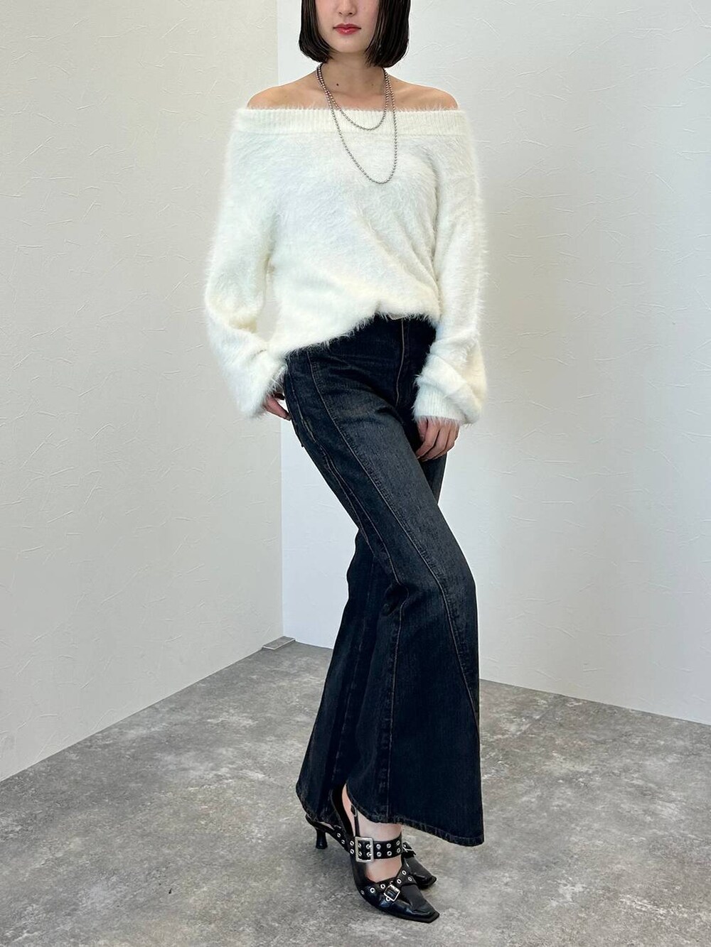 ブルー系のデニムパンツ、ブラック系のパンプス、ホワイト系のニット/セーターを着用したレディースの秋コーディネートの4枚目の写真