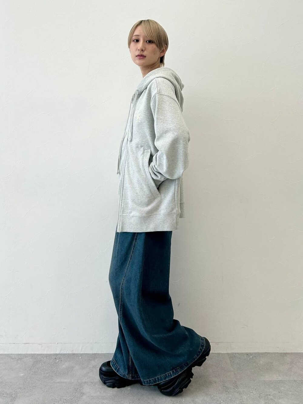 ブルー系のデニムパンツ、ブラック系のブーツ、グレー系のパーカーを着用したレディースの秋コーディネートの4枚目の写真