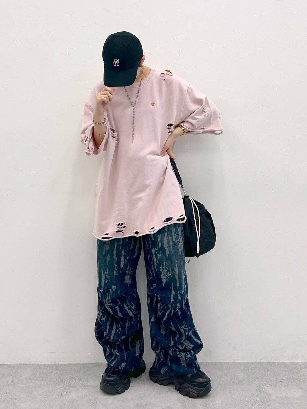 ブラック系のスニーカー、ブラック系のショルダーバッグ、ピンク系のTシャツ/カットソーを着用したレディースの夏コーディネートの2枚目の写真