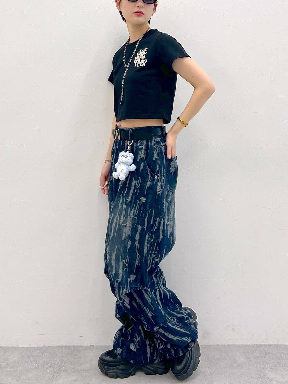 ブラック系のスニーカー、ブラック系のTシャツ/カットソー、ブルー系のデニムパンツを着用したレディースの夏コーディネートの5枚目の写真