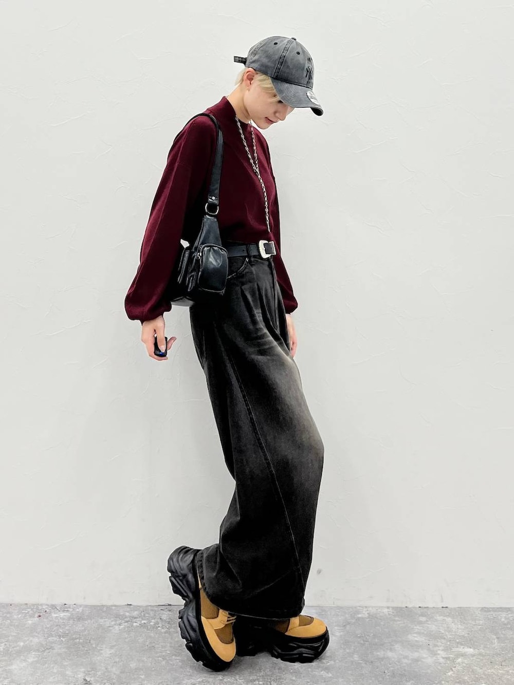 ブラック系のデニムパンツ、ブラウン系のブーツ、レッド系のニット/セーターを着用したレディースの秋コーディネートの2枚目の写真