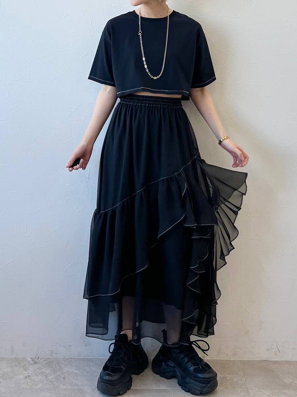 ブラック系のスニーカー、ブラック系のスカート、ブラック系のTシャツ/カットソーを着用したレディースの春コーディネートの2枚目の写真