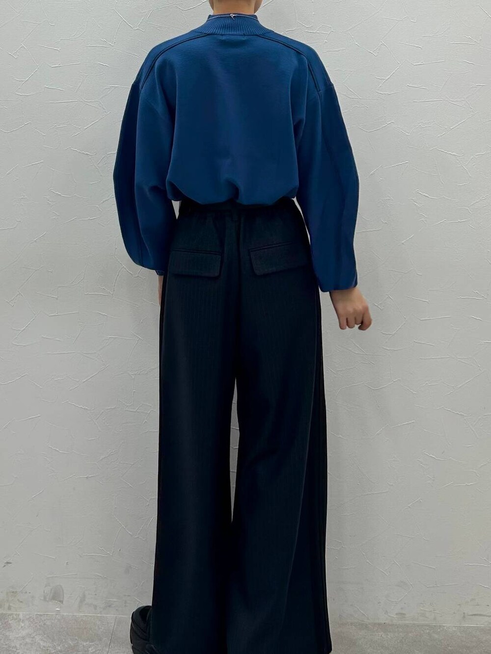 ブラック系のスニーカー、ブルー系のニット/セーター、ブラック系のスラックスを着用したレディースの秋コーディネートの7枚目の写真