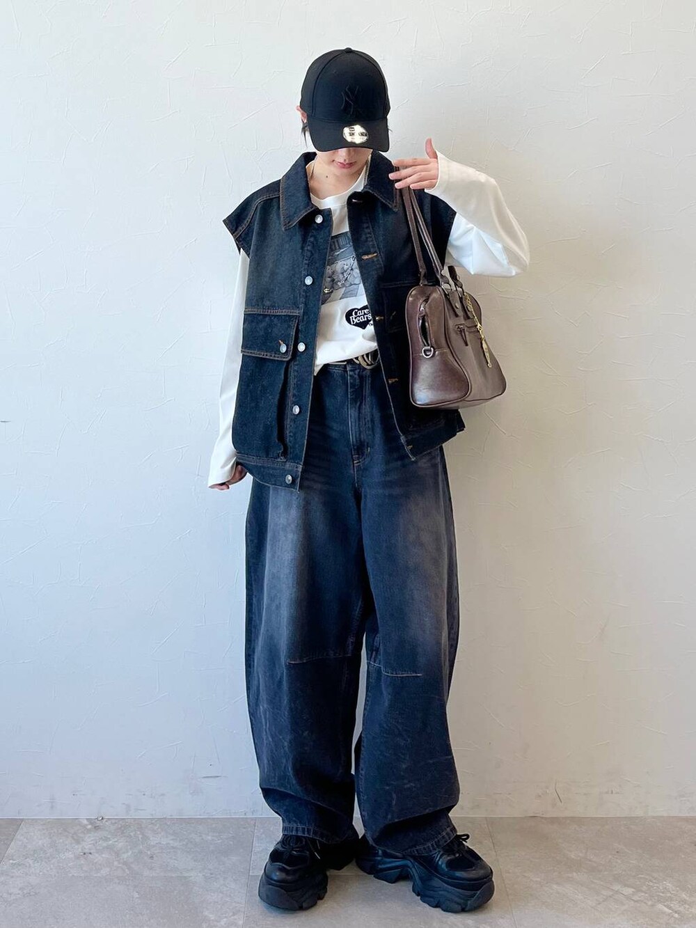 ブラック系のスニーカー、ブラック系のデニムパンツ、ブラウン系のボストンバッグを着用したレディースの春コーディネートの2枚目の写真