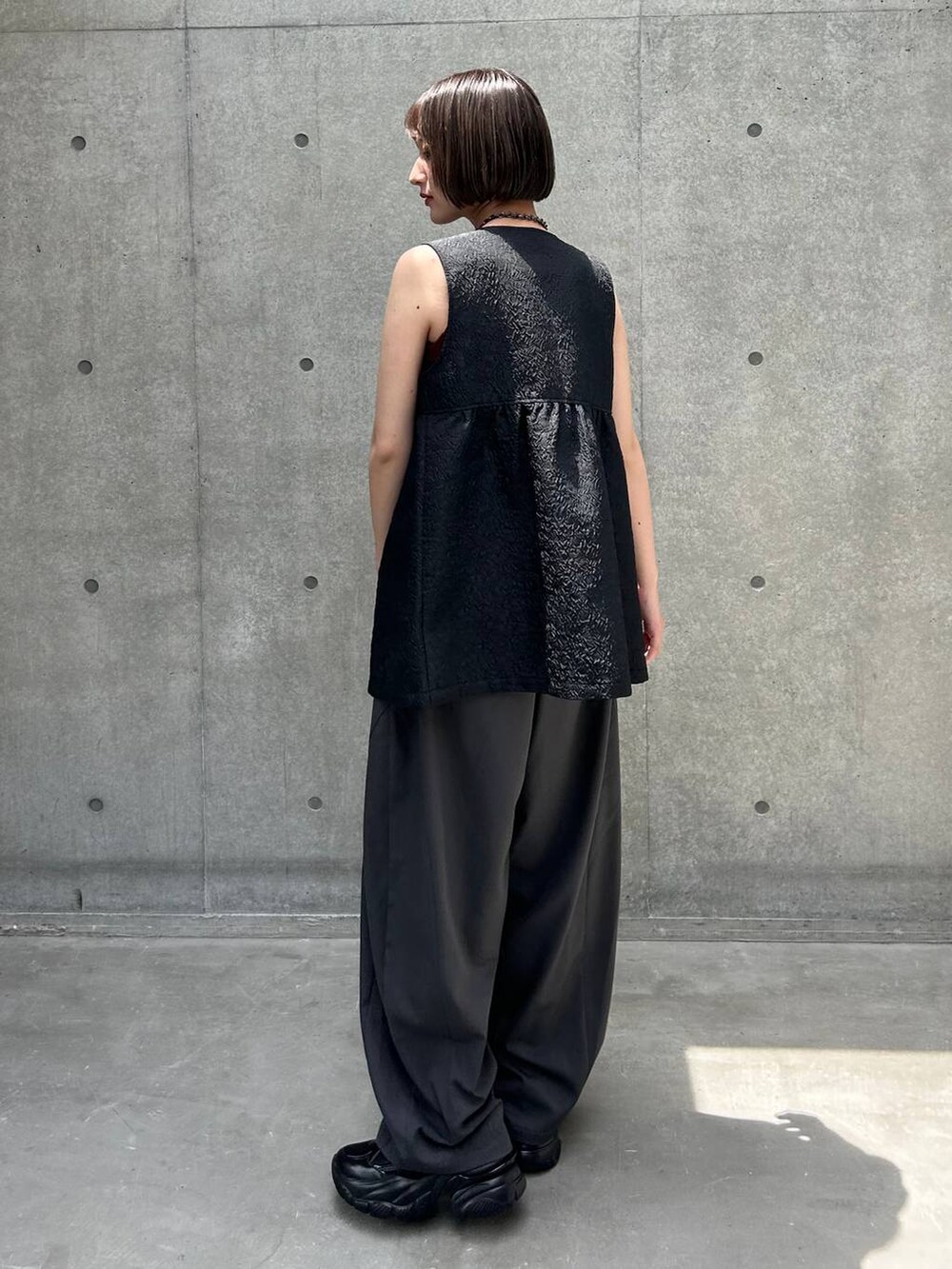 ブラック系のスニーカー、ブラック系のベスト、グレー系のその他パンツを着用したレディースの夏コーディネートの3枚目の写真