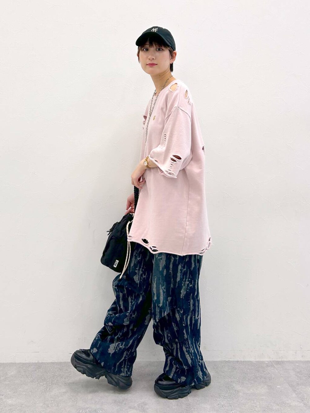 ブラック系のスニーカー、ブラック系のショルダーバッグ、ピンク系のTシャツ/カットソーを着用したレディースの夏コーディネートの4枚目の写真