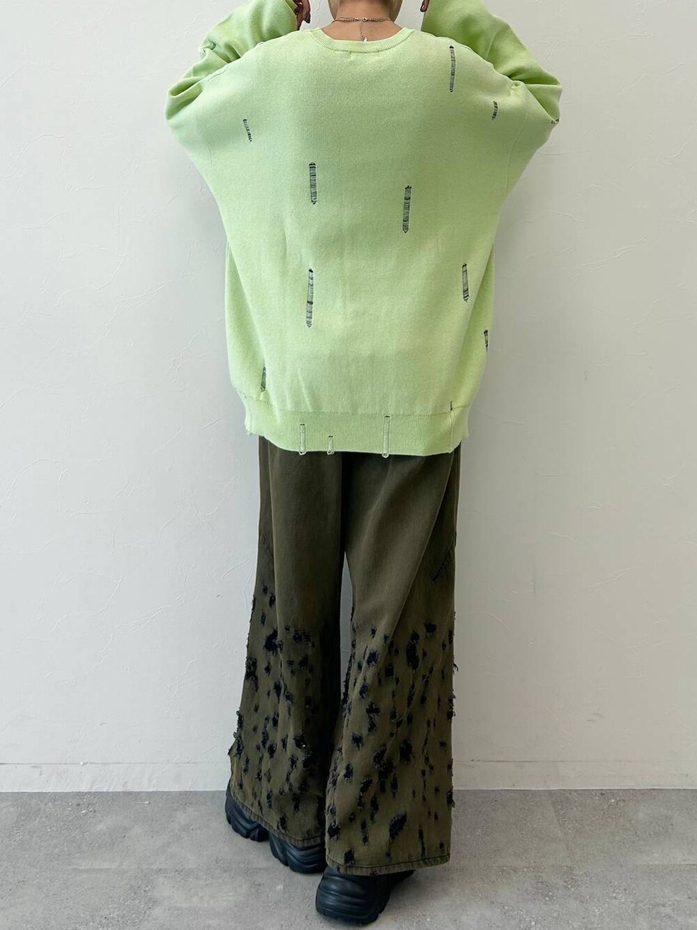 ブラック系のデニムパンツ、ブラック系のブーツ、グリーン系のニット/セーターを着用したレディースの秋コーディネートの8枚目の写真