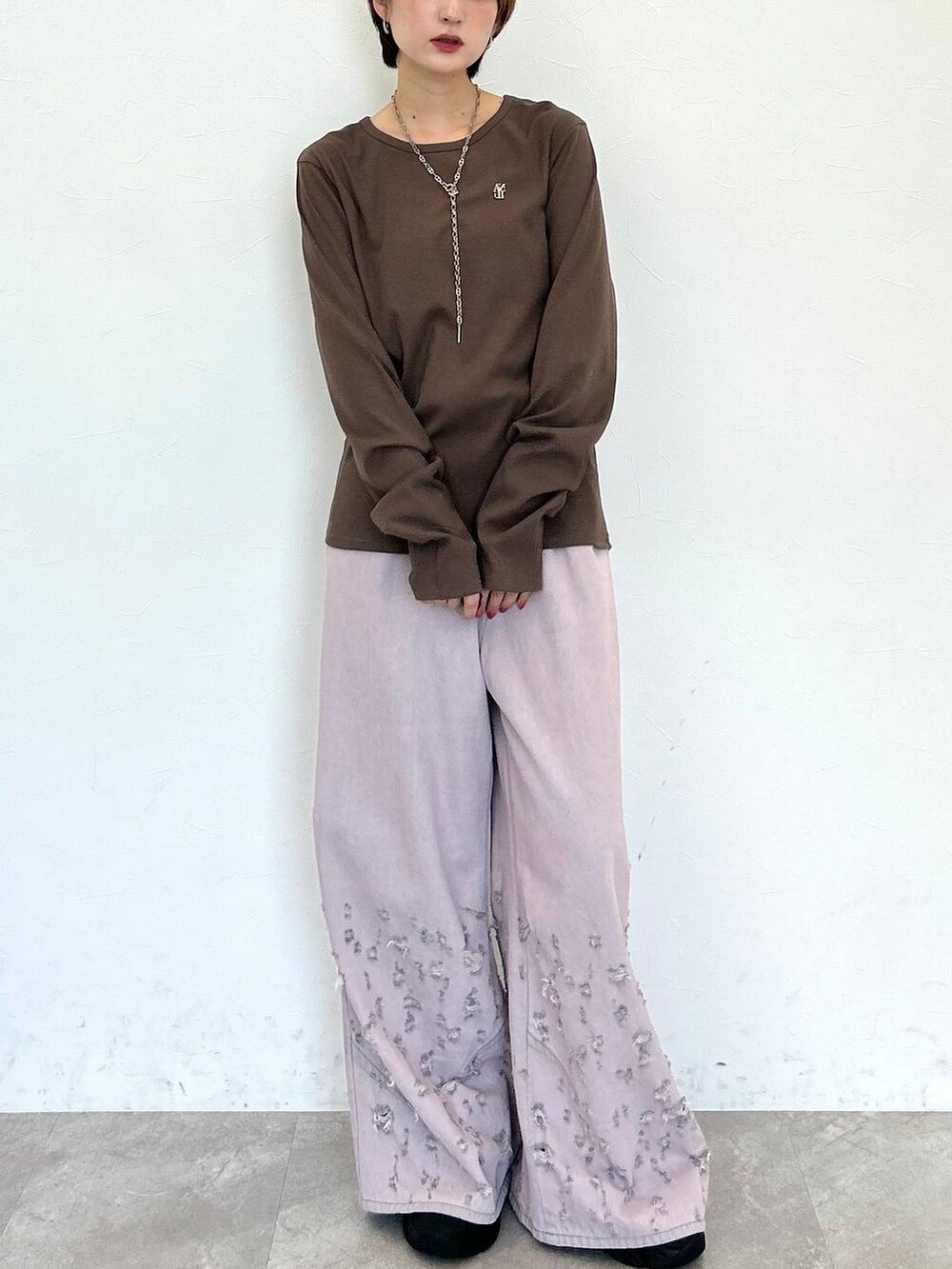 ピンク系のデニムパンツ、ブラウン系のTシャツ/カットソー、シルバー系のネックレスを着用したレディースの秋コーディネートの2枚目の写真