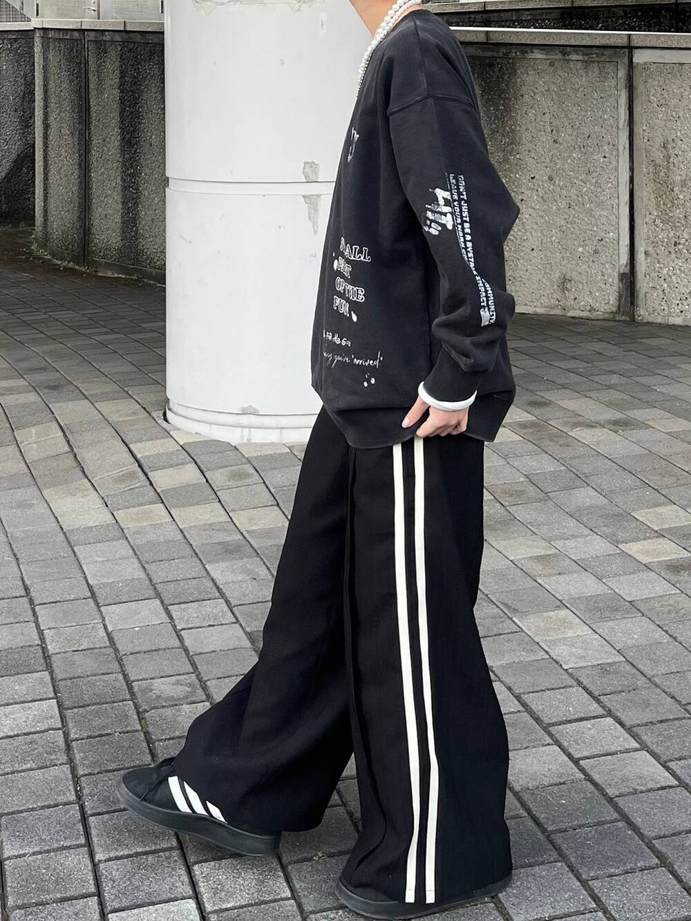 グレー系のスウェット、ブラック系のスラックス、ベージュ系のネックレスを着用したレディースの春コーディネートの4枚目の写真