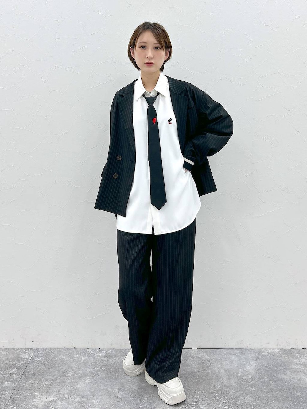 ブラック系のネクタイ、ホワイト系のシャツ/ブラウス、ブラック系のテーラードジャケットを着用したレディースの春コーディネートの2枚目の写真