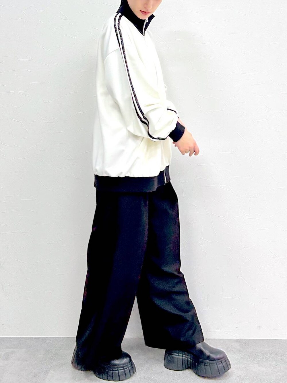 ホワイト系のその他アウター、ブラック系のスラックス、ブラック系のブーツを着用したレディースの春コーディネートの6枚目の写真