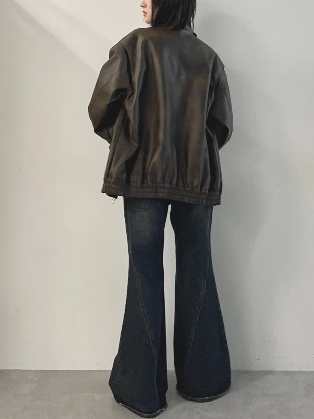 ブラック系のキャミソール、ブルー系のデニムパンツ、ブラウン系のブルゾンを着用したレディースの秋コーディネートの7枚目の写真