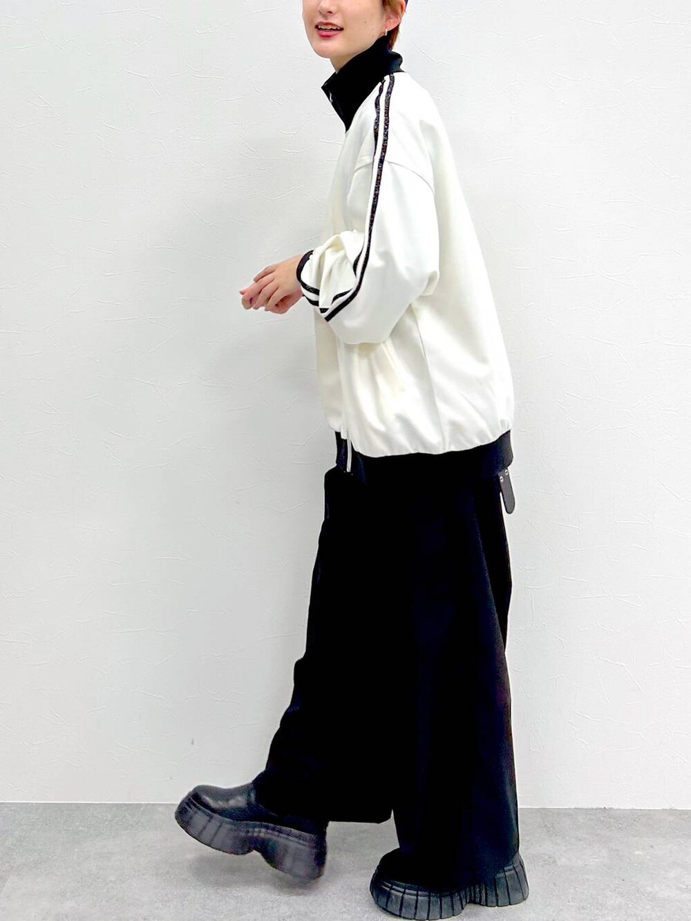 ホワイト系のその他アウター、ブラック系のスラックス、ブラック系のブーツを着用したレディースの春コーディネートの4枚目の写真