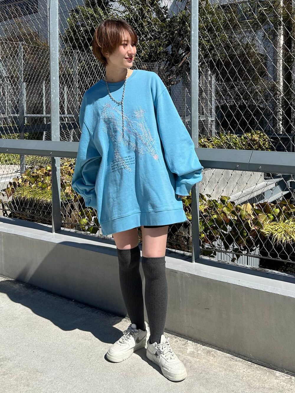 ブルー系のスウェット、シルバー系のネックレスを着用したレディースの春コーディネートの3枚目の写真