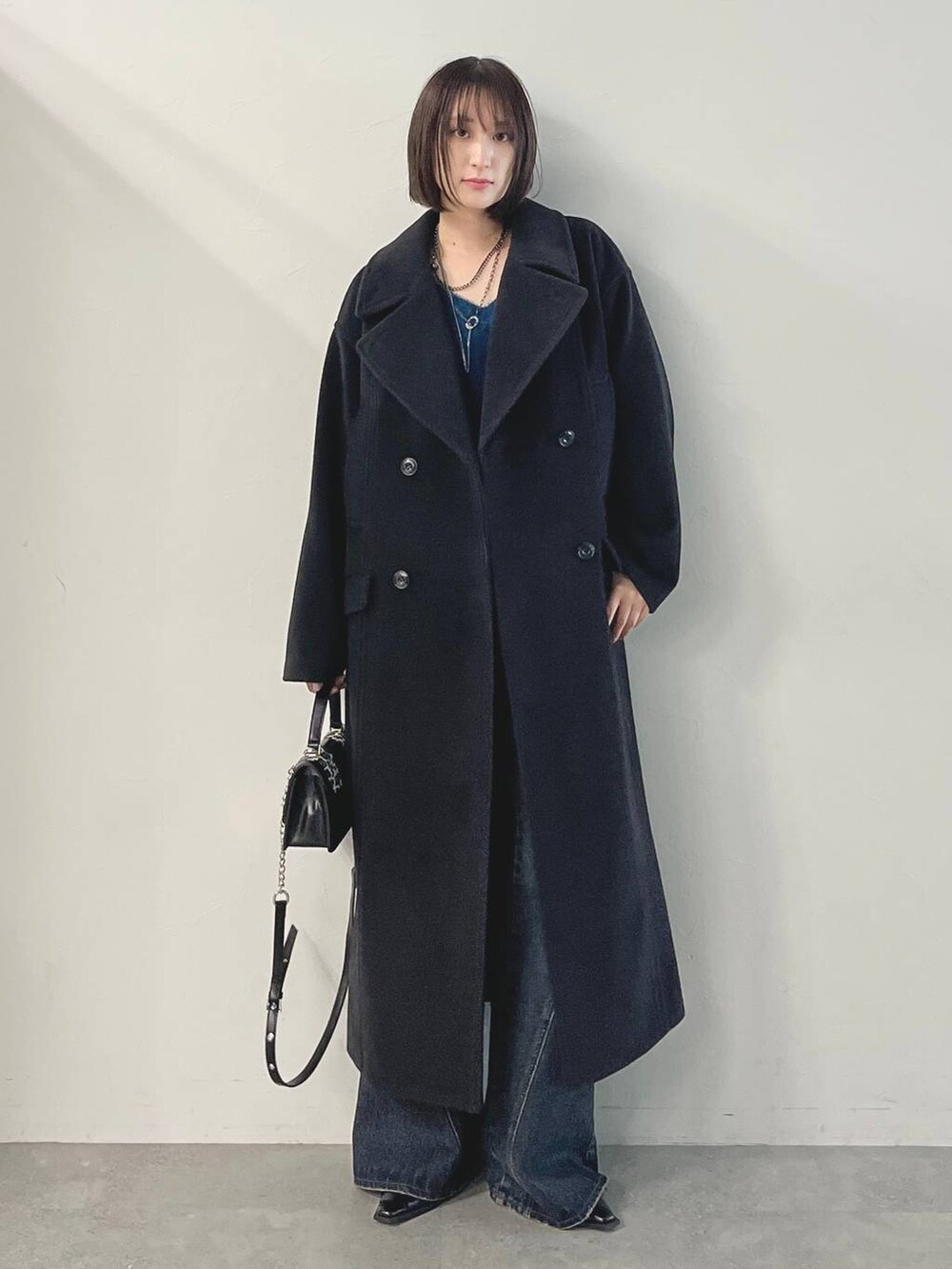 ブルー系のデニムパンツ、ブラック系のパンプス、ブラック系のチェスターコートを着用したレディースの秋コーディネートの3枚目の写真