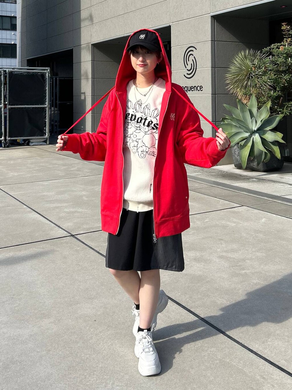 レッド系のパーカー、ホワイト系のニット/セーター、ブラック系のスラックスを着用したレディースの冬コーディネートの2枚目の写真