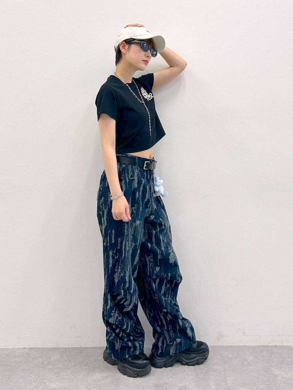 ブラック系のスニーカー、ブラック系のTシャツ/カットソー、ブルー系のデニムパンツを着用したレディースの夏コーディネートの6枚目の写真