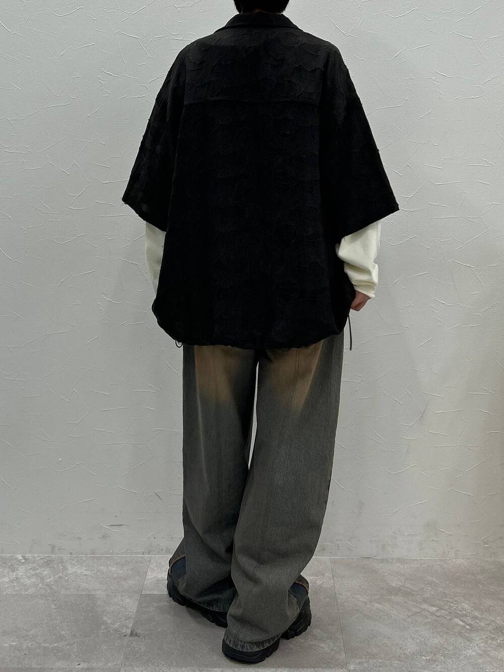 ブラック系のスニーカー、ホワイト系のTシャツ/カットソー、ブルー系のデニムパンツを着用したレディースの秋コーディネートの8枚目の写真