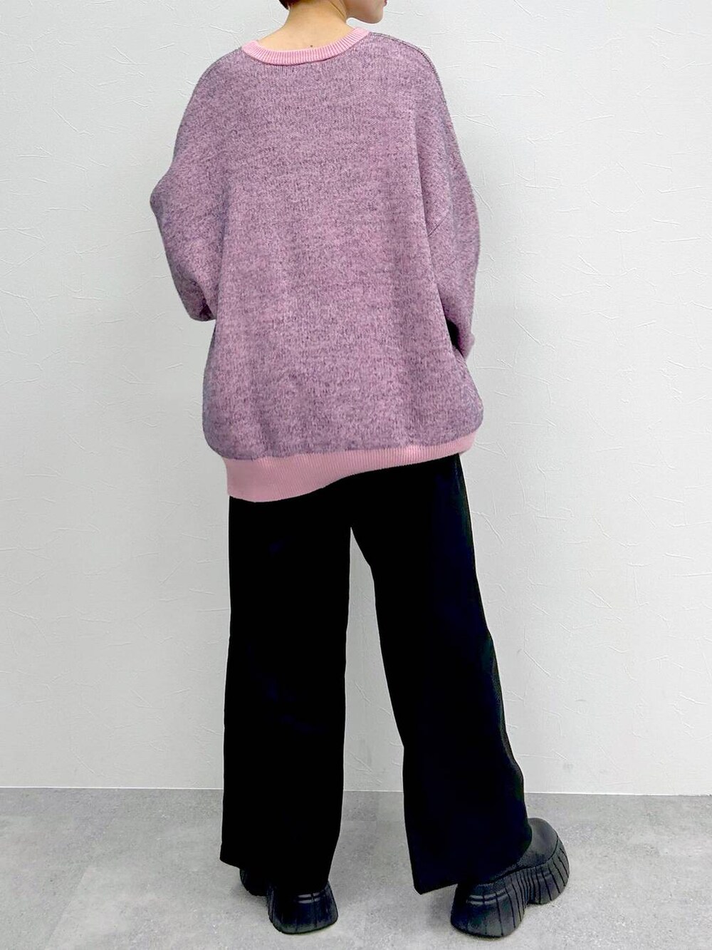 ピンク系のニット/セーター、ブラック系のブーツ、ブラック系のスラックスを着用したレディースの冬コーディネートの8枚目の写真