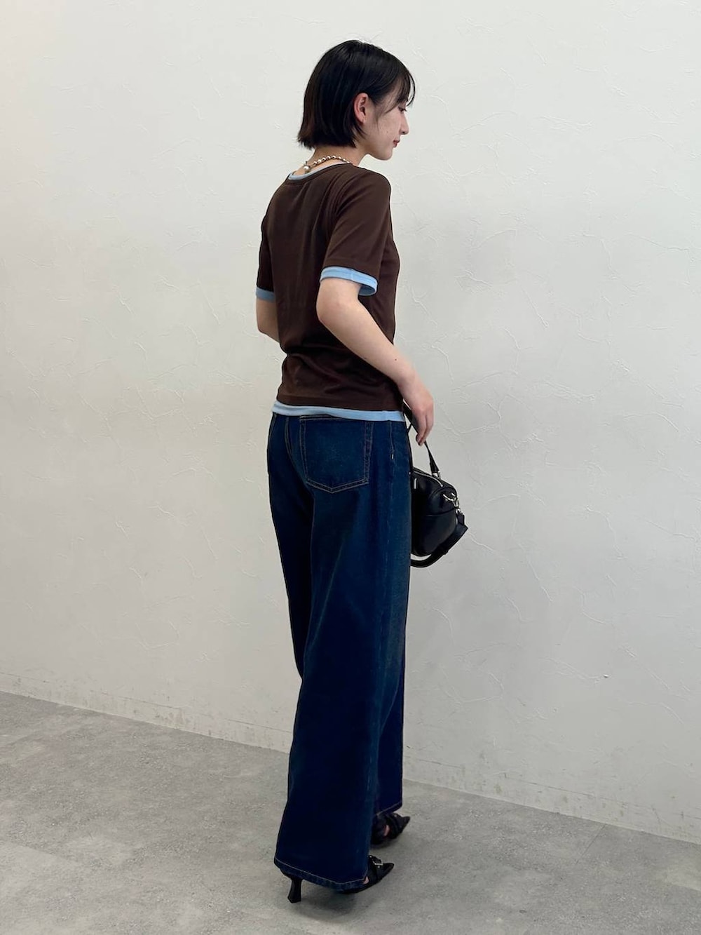 ブルー系のデニムパンツ、ブラック系のサンダル、ブラウン系のTシャツ/カットソーを着用したレディースの春コーディネートの4枚目の写真