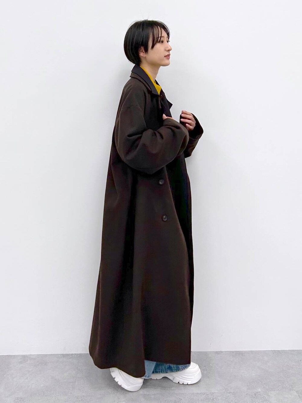 イエロー系のニット/セーター、ブルー系のデニムパンツ、ブラウン系のその他アウターを着用したレディースの秋コーディネートの5枚目の写真