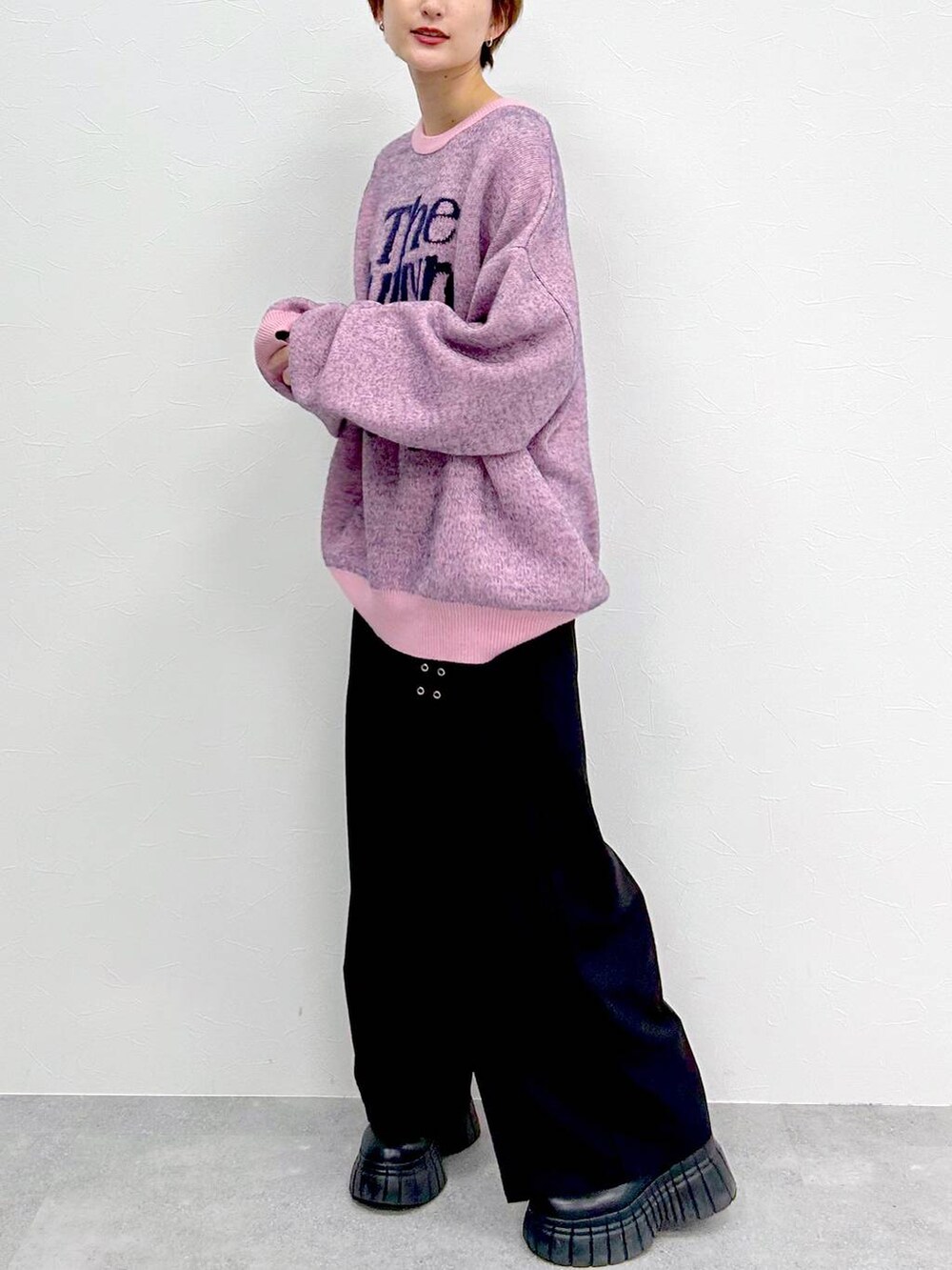 ピンク系のニット/セーター、ブラック系のブーツ、ブラック系のスラックスを着用したレディースの冬コーディネートの4枚目の写真