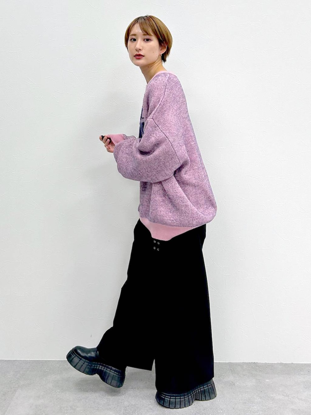 ピンク系のニット/セーター、ブラック系のブーツ、ブラック系のスラックスを着用したレディースの冬コーディネートの3枚目の写真