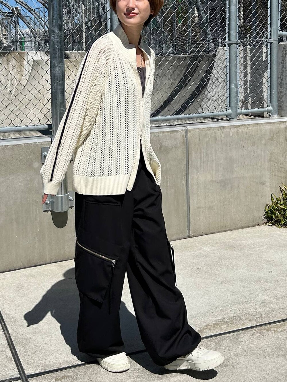 グレー系のタンクトップ、ホワイト系のカーディガン/ボレロ、ブラック系のスラックスを着用したレディースの春コーディネートの4枚目の写真