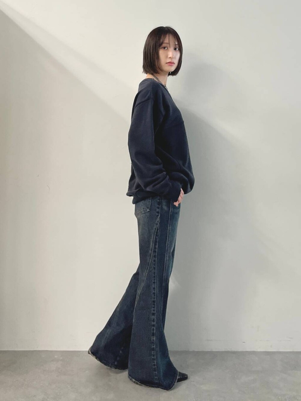 ブルー系のデニムパンツ、ブラック系のパンプス、グレー系のスウェットを着用したレディースの秋コーディネートの6枚目の写真