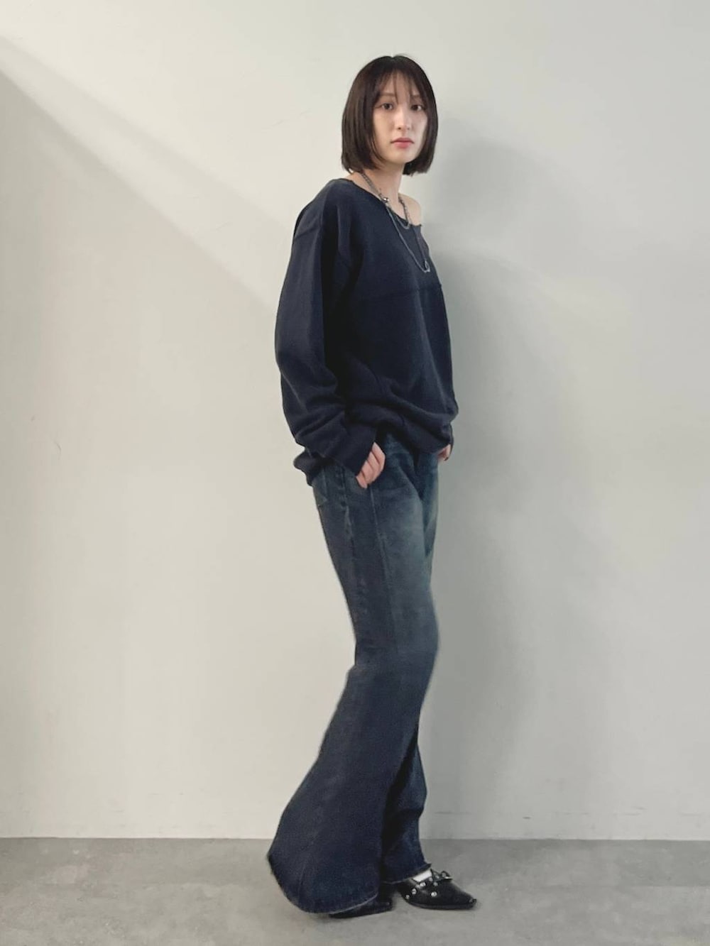 ブルー系のデニムパンツ、ブラック系のパンプス、グレー系のスウェットを着用したレディースの秋コーディネートの5枚目の写真