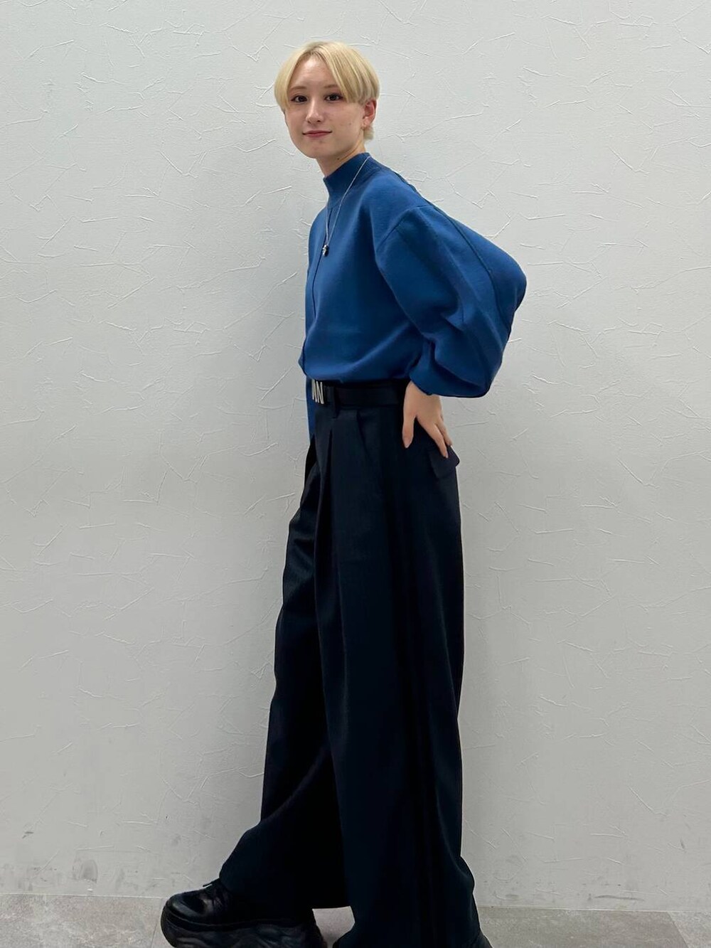 ブラック系のスニーカー、ブルー系のニット/セーター、ブラック系のスラックスを着用したレディースの秋コーディネートの2枚目の写真