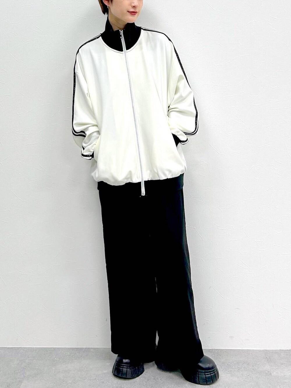 ホワイト系のその他アウター、ブラック系のスラックス、ブラック系のブーツを着用したレディースの春コーディネートの2枚目の写真