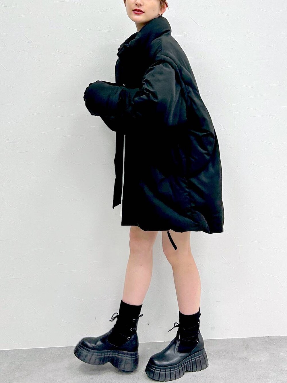 ブラック系のブルゾン、ブラック系のブーツ、ブラック系のスカートを着用したレディースの冬コーディネートの7枚目の写真