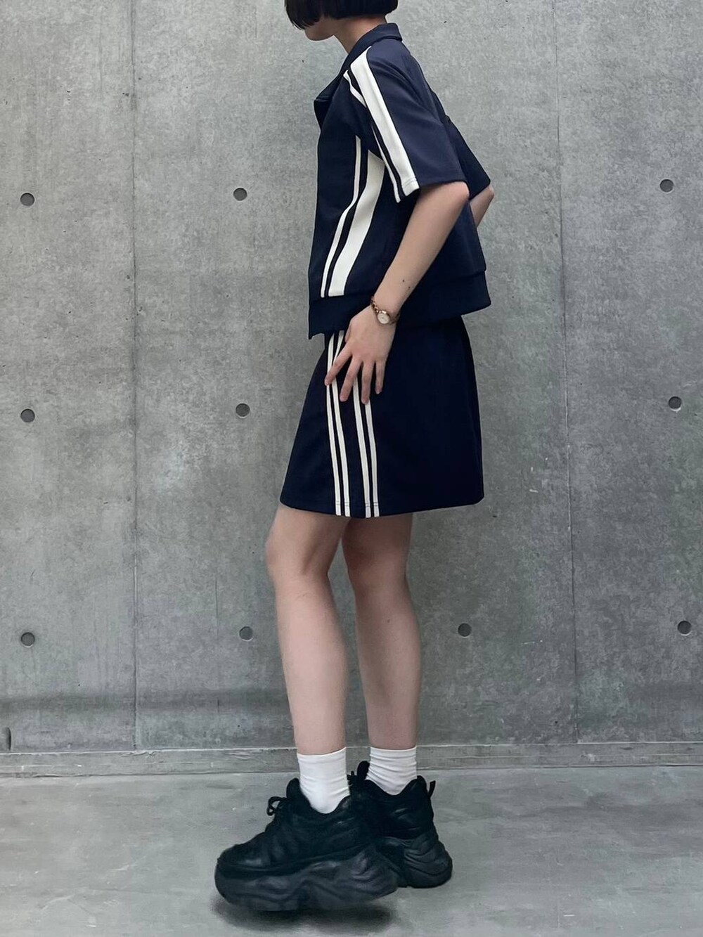 ブラック系のスニーカー、ブラック系のキャミソール、ブルー系のスカートを着用したレディースの夏コーディネートの4枚目の写真