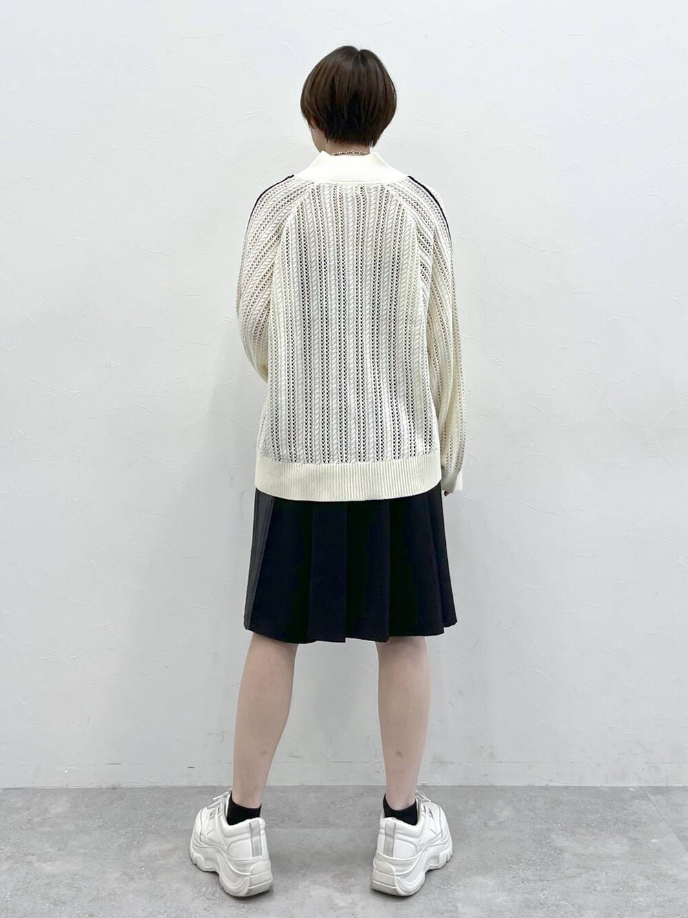 ブラック系のスラックス、ホワイト系のカーディガン/ボレロ、シルバー系のネックレスを着用したレディースの冬コーディネートの7枚目の写真