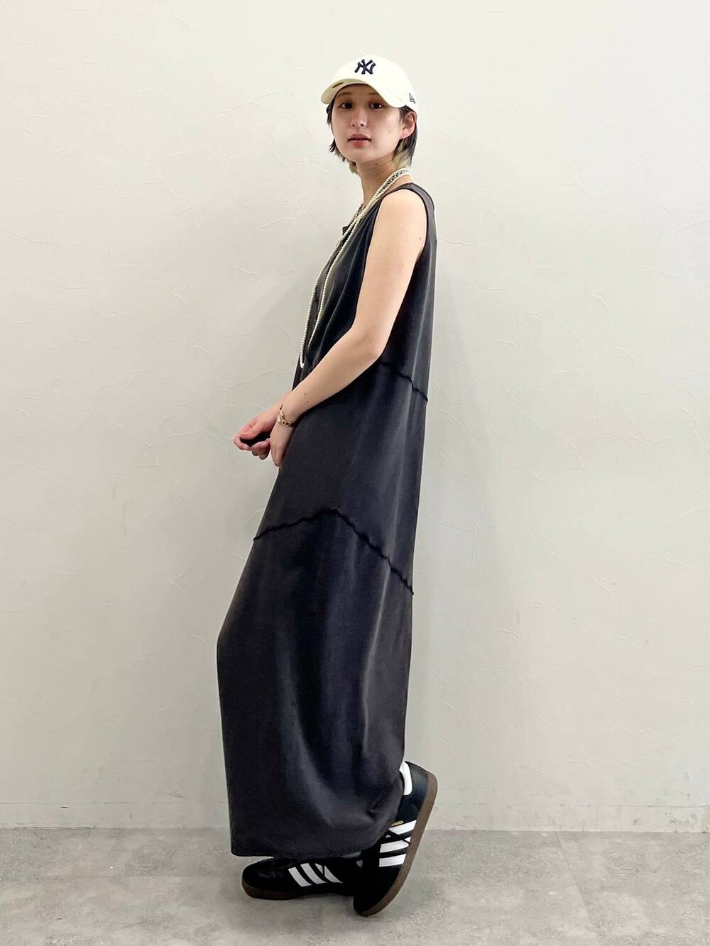 ブラック系のスニーカー、ブラック系のワンピース、ホワイト系のネックレスを着用したレディースの春コーディネートの2枚目の写真