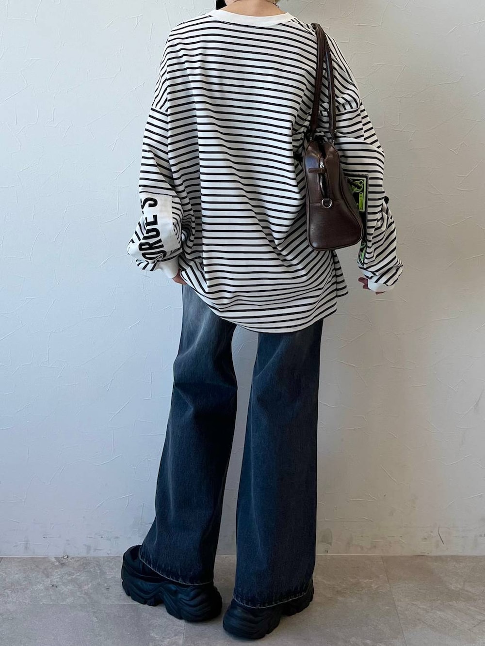 ブラック系のスニーカー、ブラウン系のボストンバッグ、ブラック系のデニムパンツを着用したレディースの春コーディネートの6枚目の写真