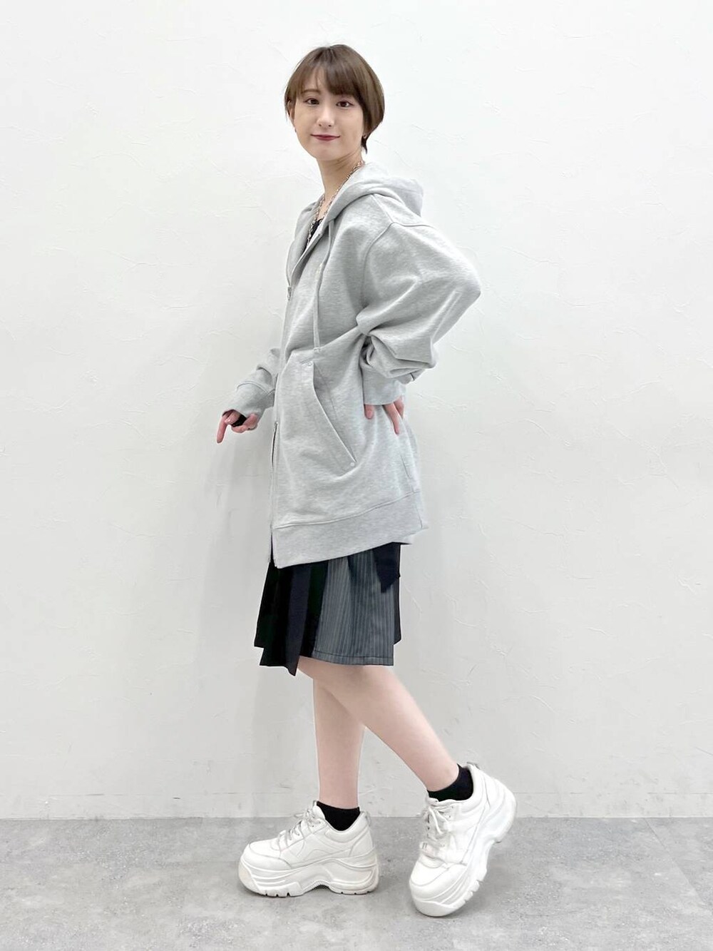 グレー系のパーカー、ブラック系のスラックスを着用したレディースの春コーディネートの3枚目の写真