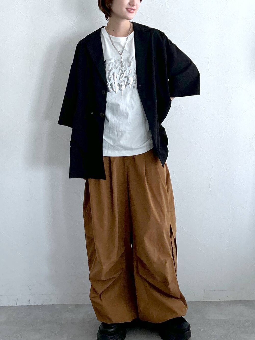 ブラック系のテーラードジャケット、ブラウン系のカーゴパンツ、ホワイト系のTシャツ/カットソーを着用したレディースの春コーディネートの3枚目の写真