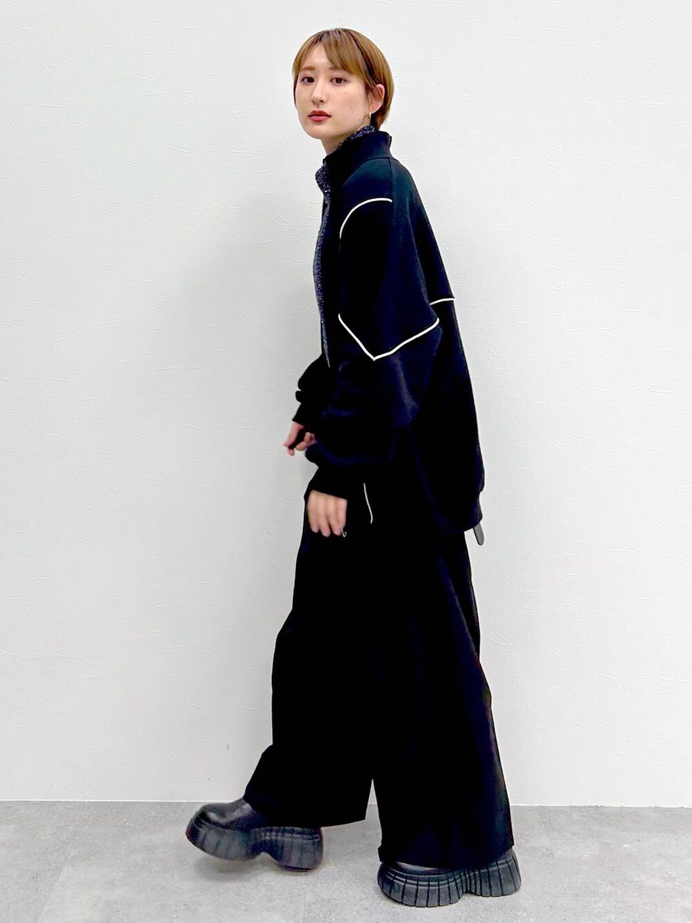 ブラック系のスウェット、ブラック系のブーツ、ブラック系のスラックスを着用したレディースの冬コーディネートの4枚目の写真