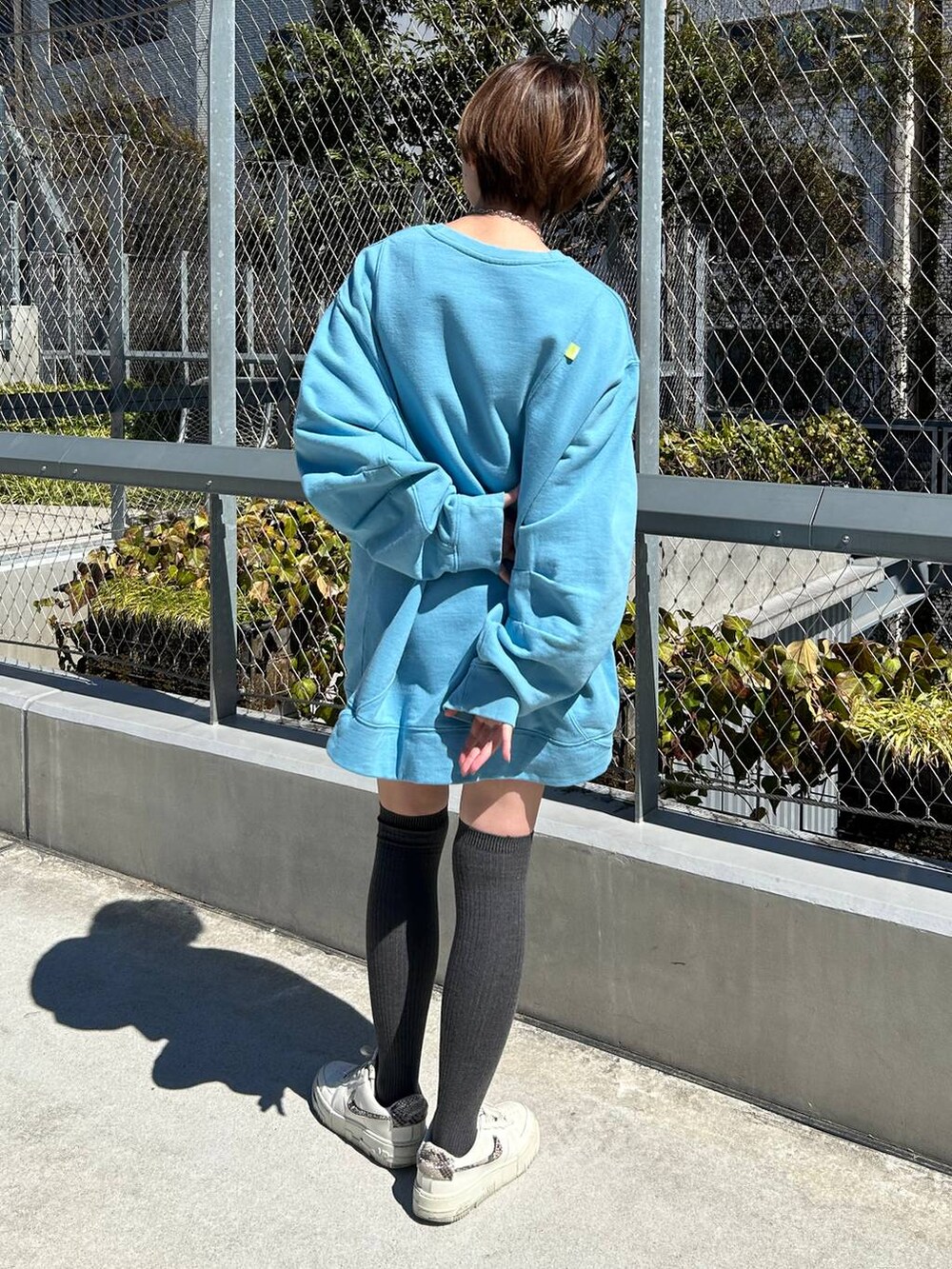 ブルー系のスウェット、シルバー系のネックレスを着用したレディースの春コーディネートの2枚目の写真