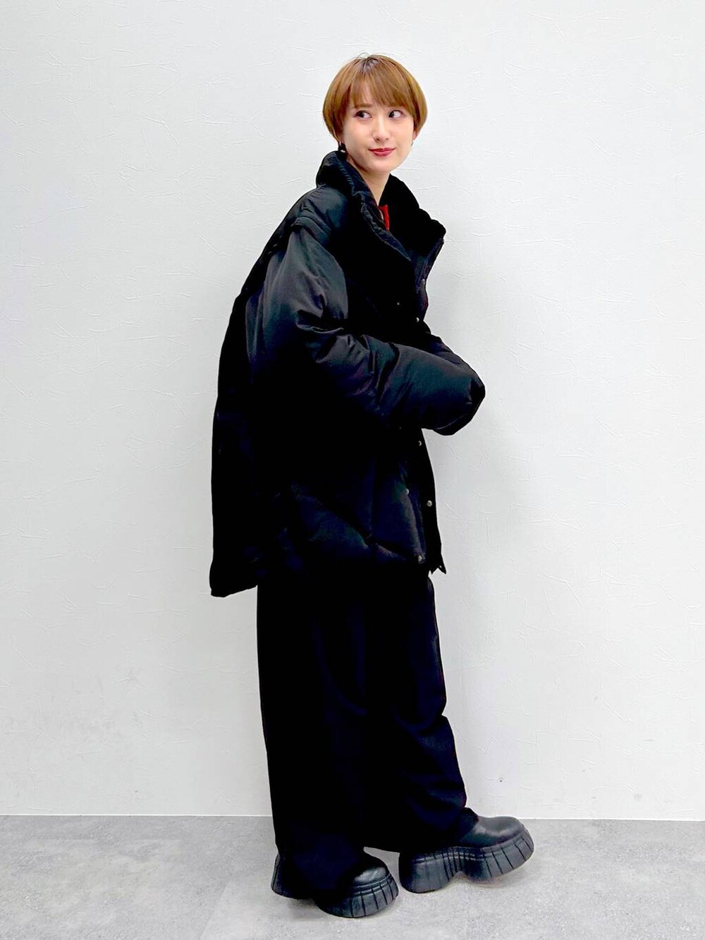 ブラック系のブルゾン、レッド系のニット/セーター、ブラック系のスラックスを着用したレディースの冬コーディネートの5枚目の写真