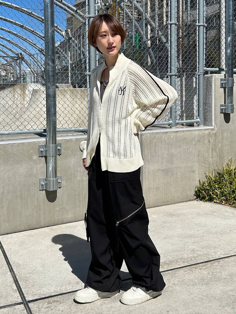 グレー系のタンクトップ、ホワイト系のカーディガン/ボレロ、ブラック系のスラックスを着用したレディースの春コーディネートの2枚目の写真